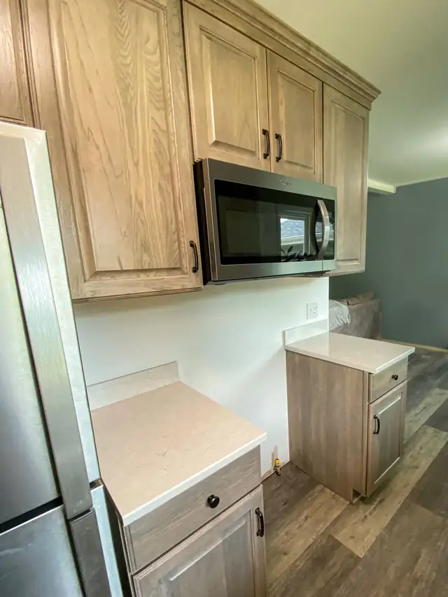 Cambridge, Iowa kitchen renovation with gray-brown stained cabinets, microwave above the range area and light quartz counters